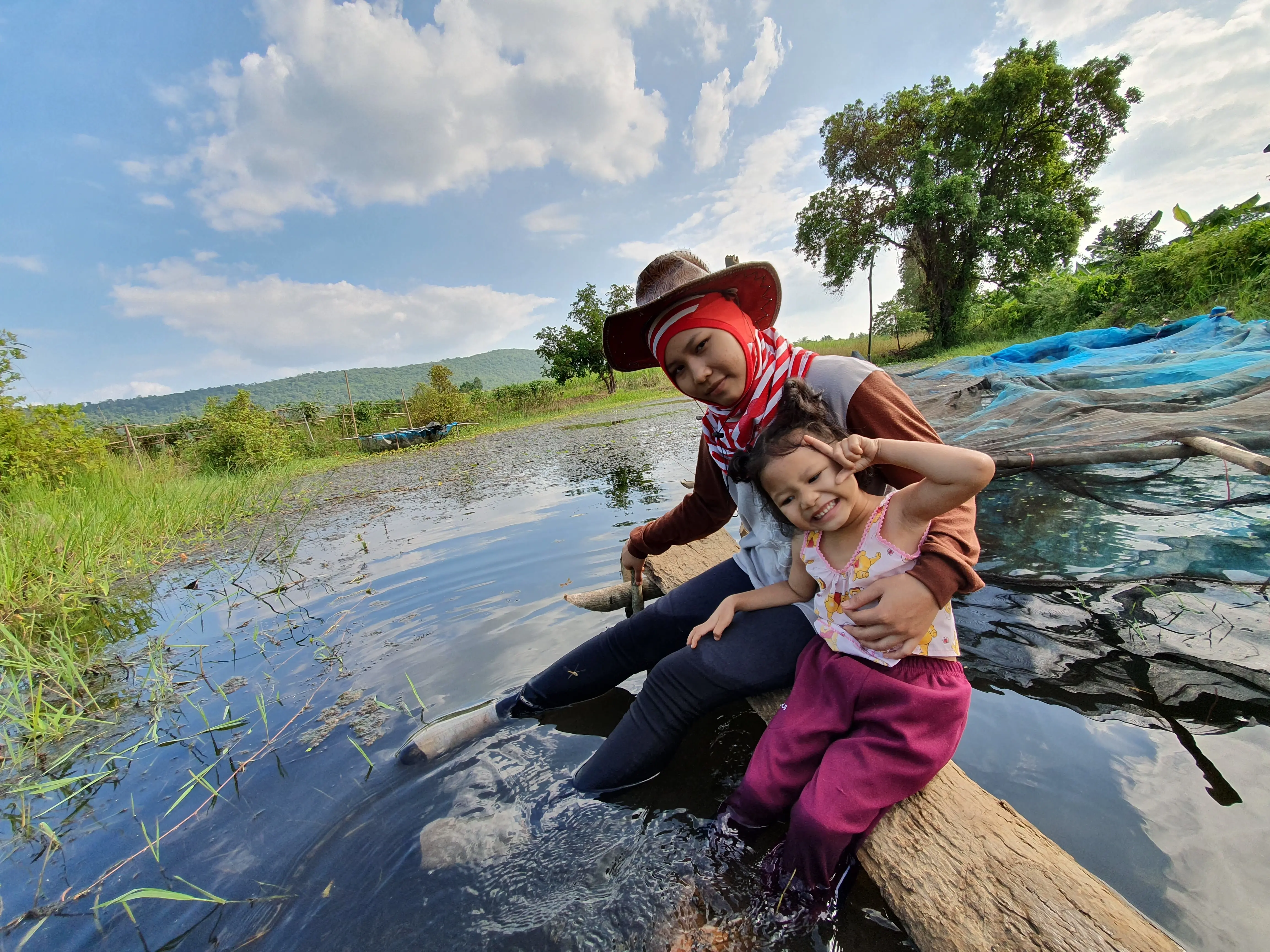 Rückenansicht einer Frau mit erhobenen Armen vor dem Himmel.