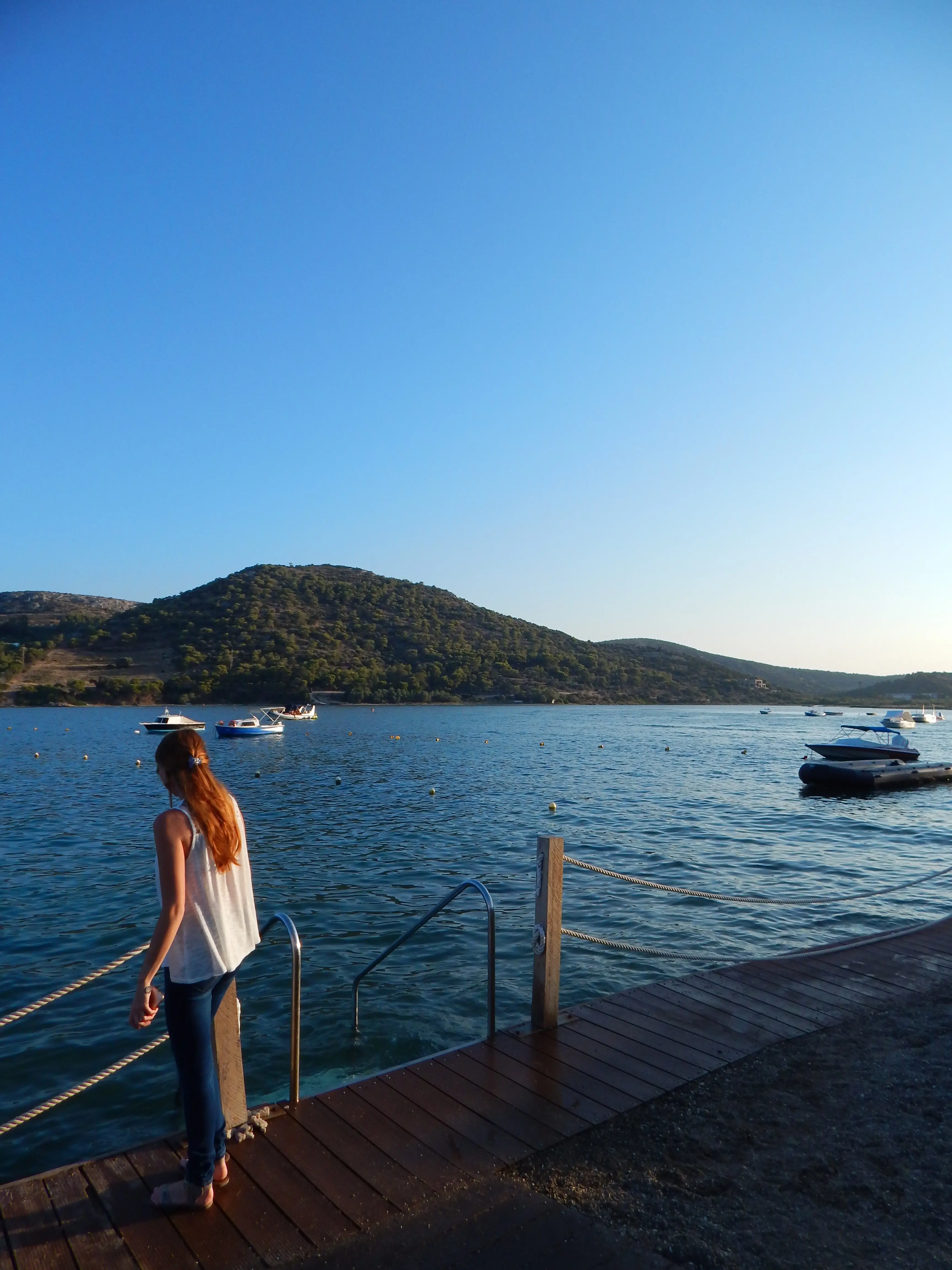 Eine Frau steht im Meer vor einem klaren blauen Himmel.